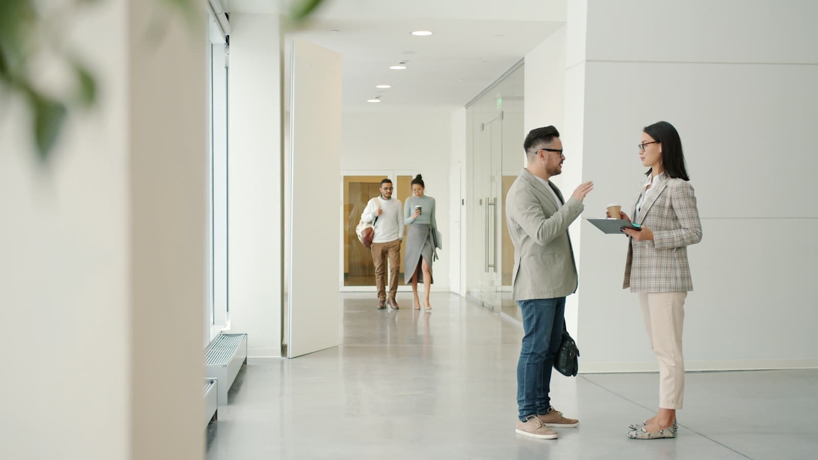 Two people talking in a modern office hallway