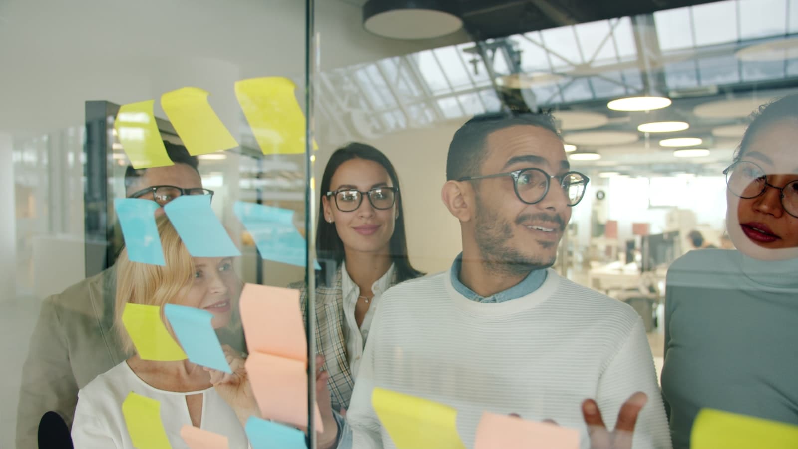 Diverse team brainstorming with sticky notes on glass